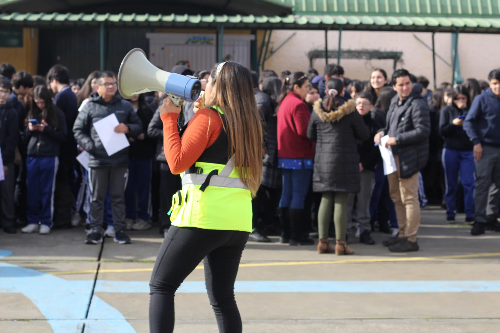 Monitora TERO con megáfono coordinando la evacuación de estudiantes en la zona de seguridad del colegio